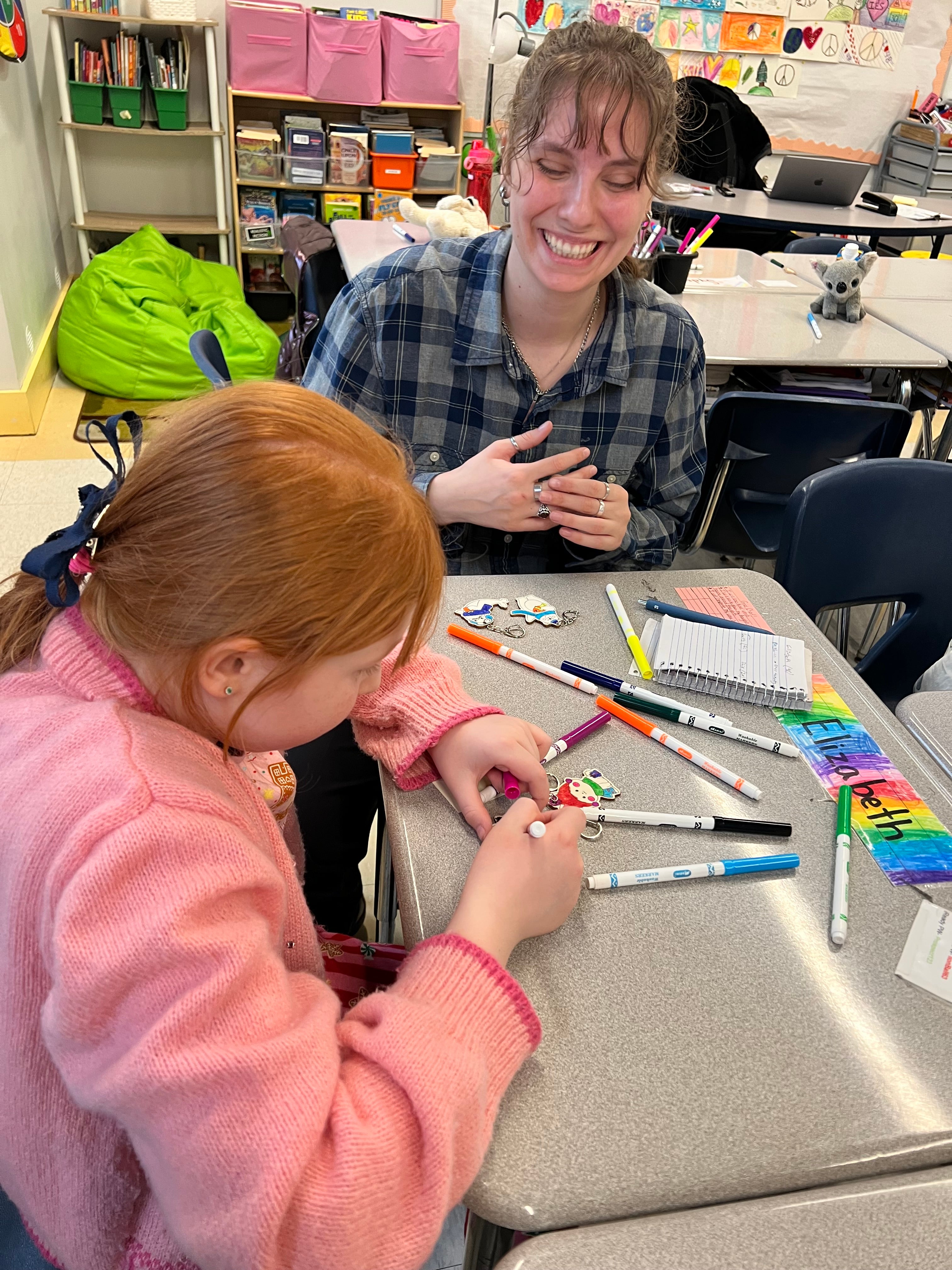 Student coloring a wooden holiday ornament alongside an educator during an Etchline NYC workshop at International Elementary School