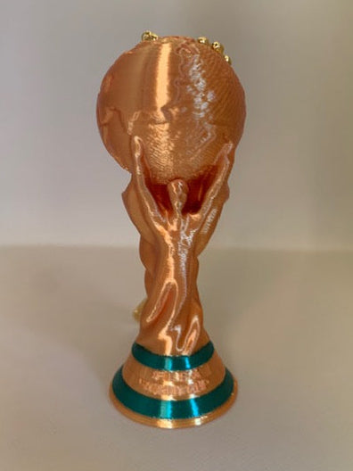 Front view of a 3D printed FIFA World Cup Trophy keychain in shiny gold with green base accents and gold bead chain hardware.