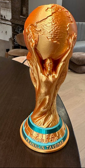 Gold FIFA World Cup trophy in large size on a table in an indoor setting personalized with the name "Franklin Taveras".