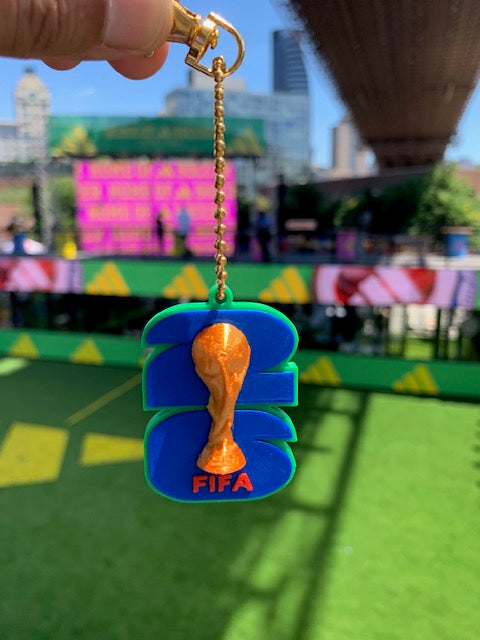 FIFA World Cup can tab opener keychain with trophy design held at a soccer event under the Brooklyn Bridge