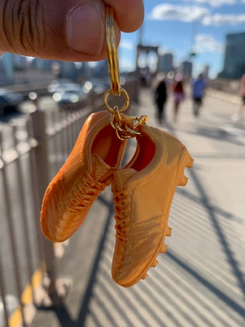 Golden Boot soccer cleats keychain held on the Brooklyn Bridge