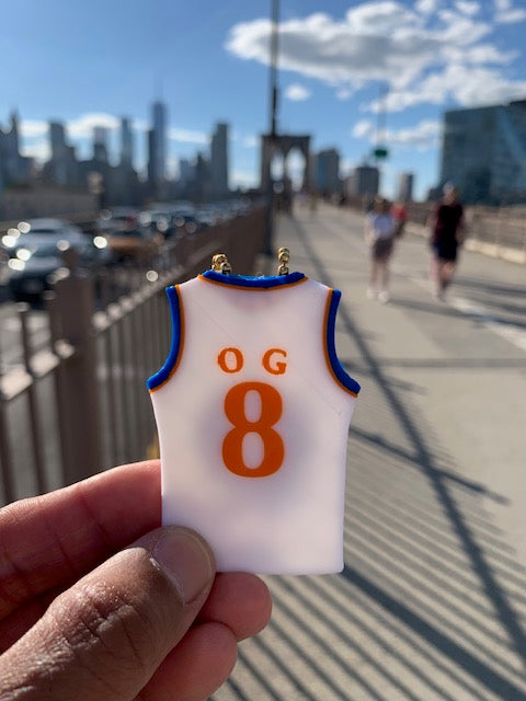 White OG #8 Knicks-inspired jersey keychain held up on NYC's Brooklyn Bridge.